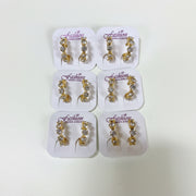 Womens gold-tone hoop earrings lined with sparkling round rhinestones displayed on white card packaging