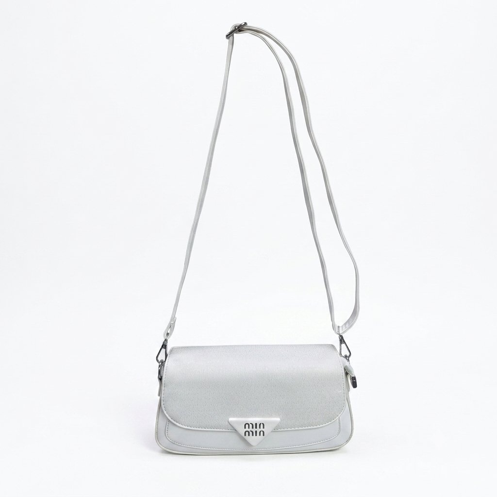 A light gray shoulder bag with a long strap and a silver triangular logo plaque on the front flap, shown against a plain white background.